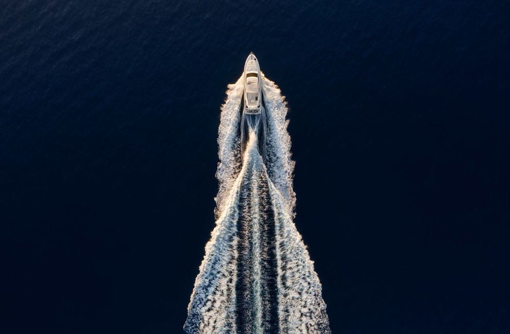 Aerial view of a yacht on the ocean heading toward Miami.